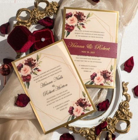 a wedding invitation with a gold border and red flowers